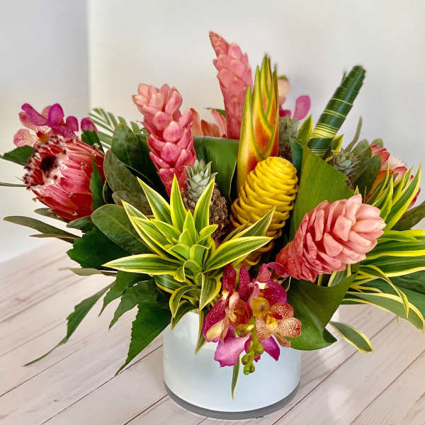 Tropical flower arrangement in a white vase with pink and yellow blooms