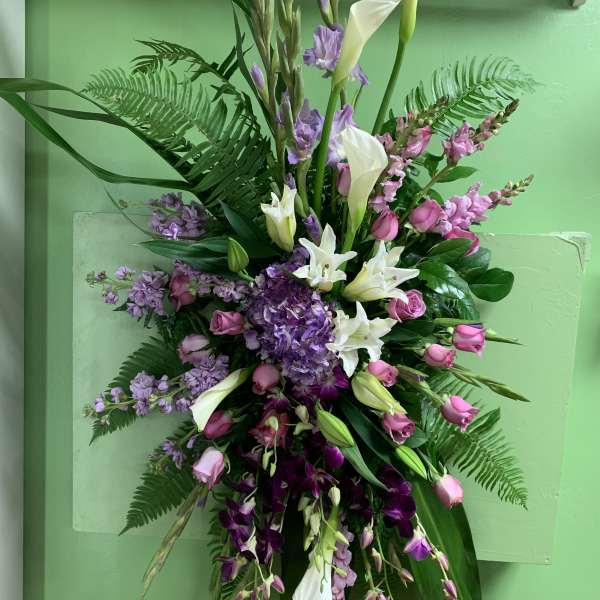 Tall floral spray with white calla lilies, pink roses, and purple blooms