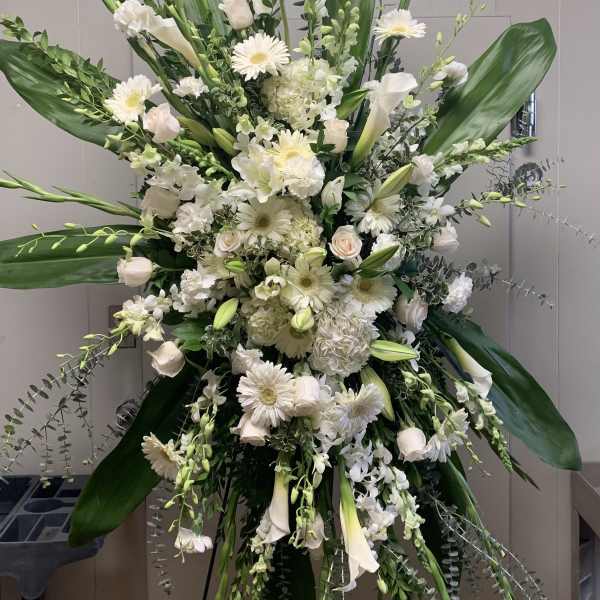Large white floral standing spray with lilies, roses, and daisies