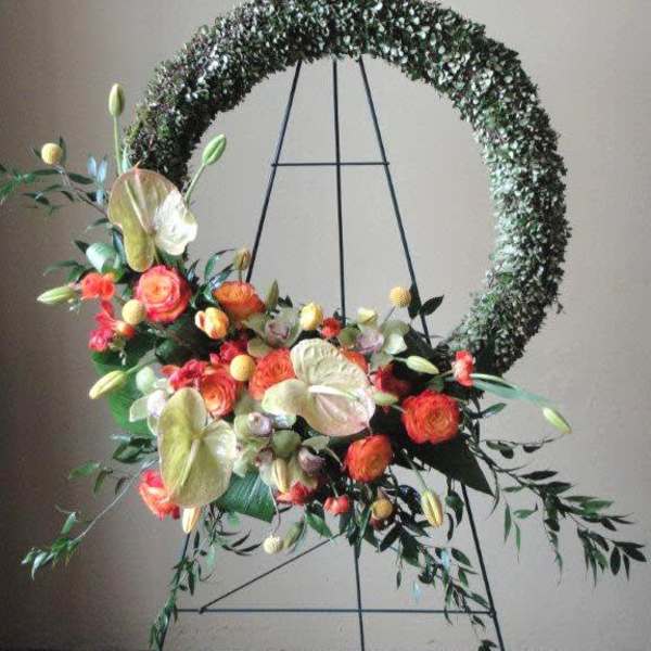 Floral wreath on a metal stand with orange and cream blooms