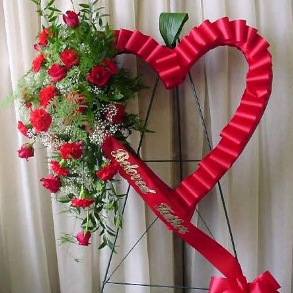 Heart-shaped floral standing spray with red roses and a red ribbon bow