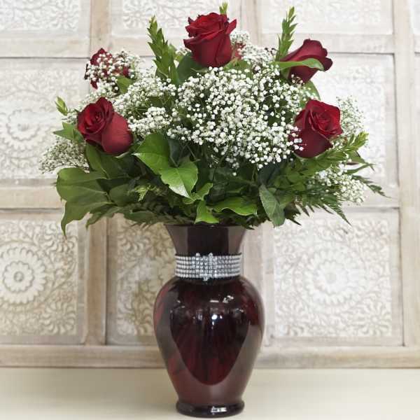 Red roses and baby's breath in a burgundy vase with a rhinestone band
