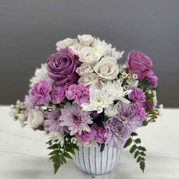 Bouquet of pink, purple, and white flowers in a striped vase