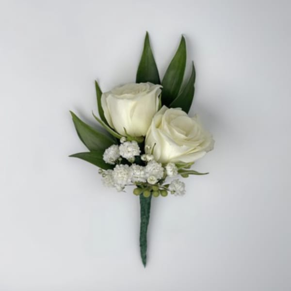 White rose boutonniere with small white filler flowers and green leaves