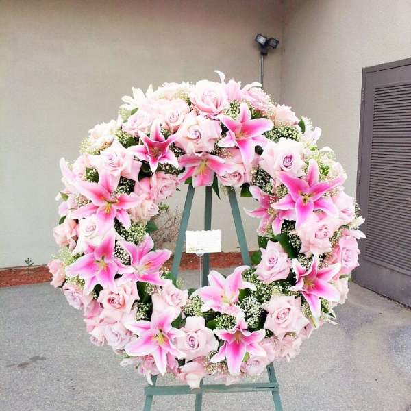 Large pink floral wreath on a stand with roses and lilies