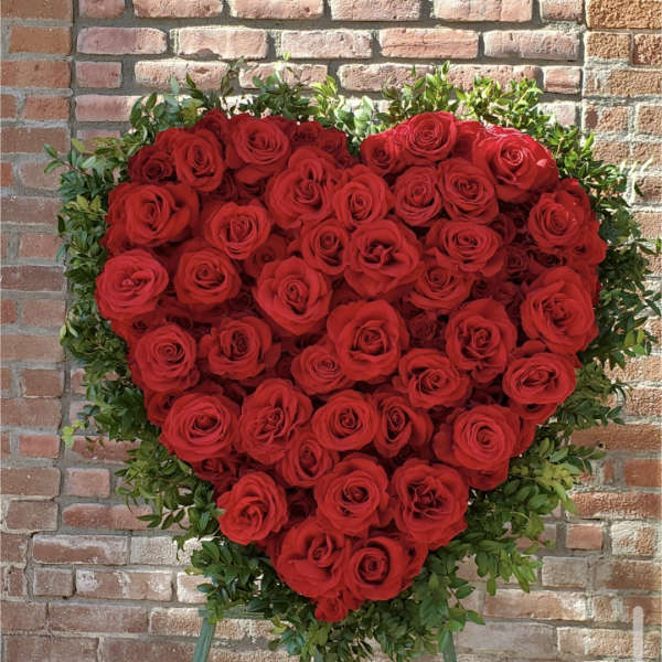 Heart-shaped arrangement of red roses with green foliage on an easel