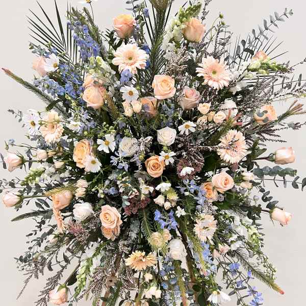 Large standing floral spray with peach roses and blue delphinium