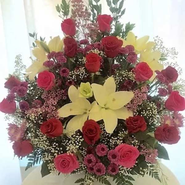 Tall bouquet of red roses and yellow lilies with pink filler flowers