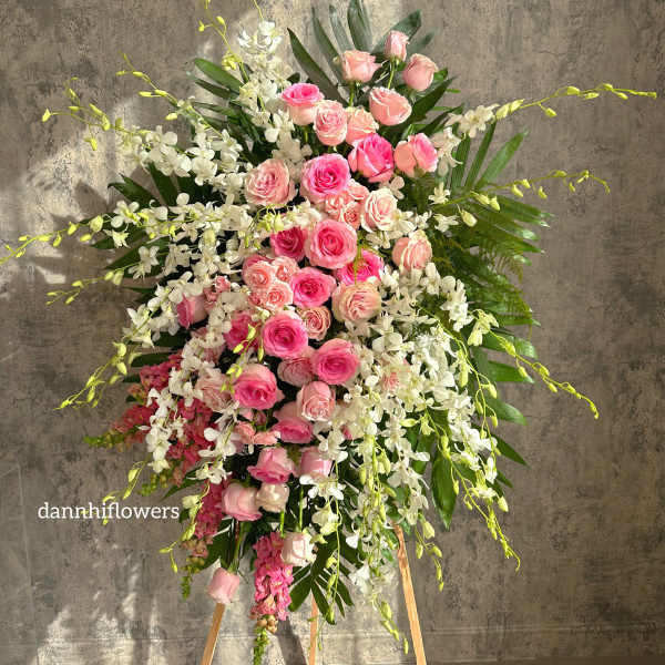 Tall standing arrangement of pink roses and white orchids on an easel