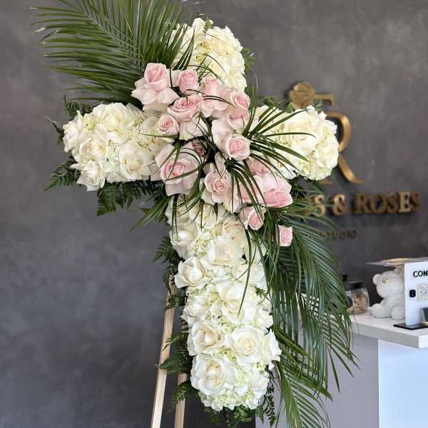 Large cross-shaped floral arrangement of white and pink roses