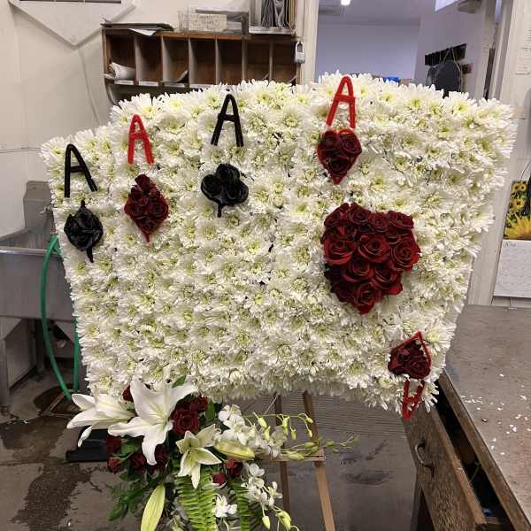 Large floral tribute board with white chrysanthemums, red roses, and lilies