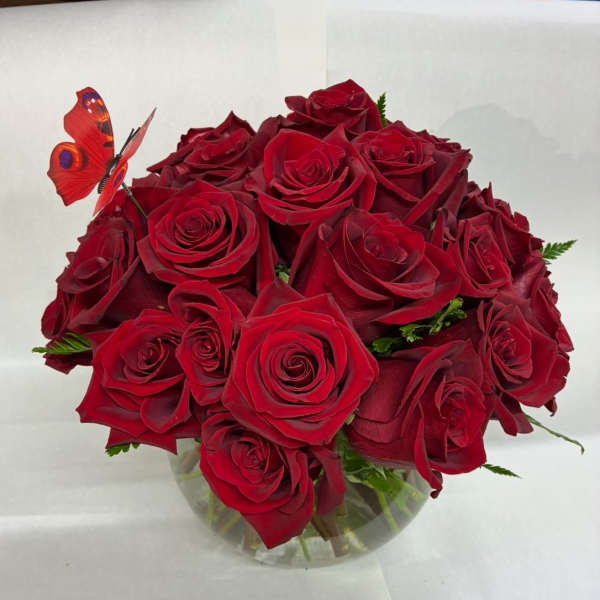 Bouquet of red roses in a clear glass vase with a butterfly pick
