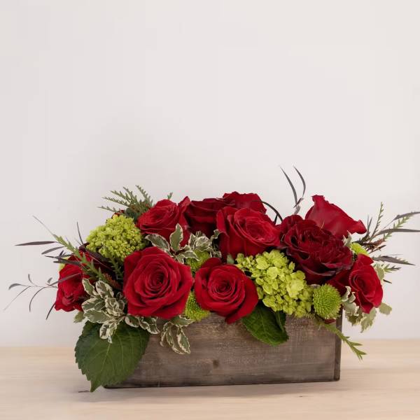 Red roses and green hydrangeas arranged in a wooden box