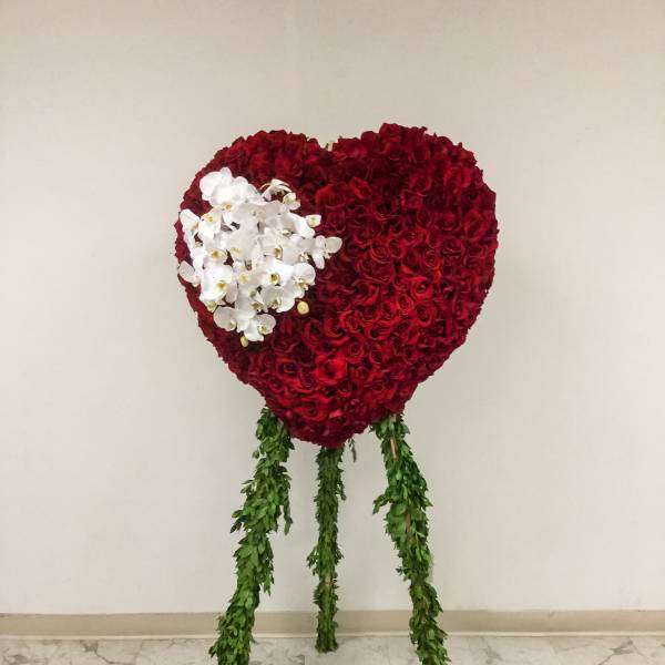 Heart-shaped red rose arrangement with white orchids and hanging greenery