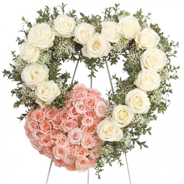 Heart-shaped floral wreath with white and pink roses on a stand