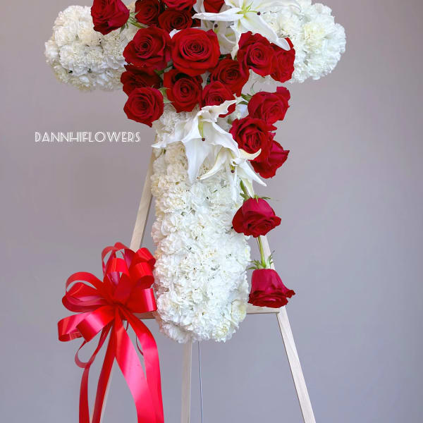 Red roses and white carnations arranged on a standing easel with a red ribbon bow