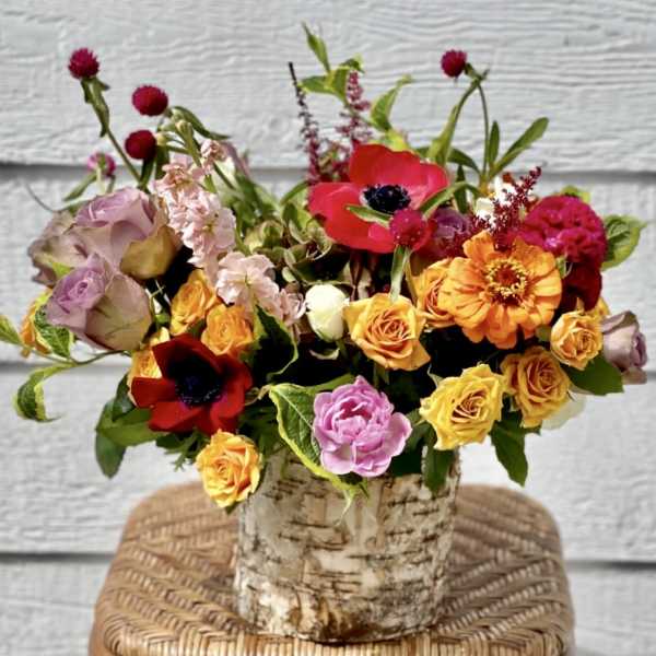 Colorful bouquet of roses and mixed blooms in a birch-style container