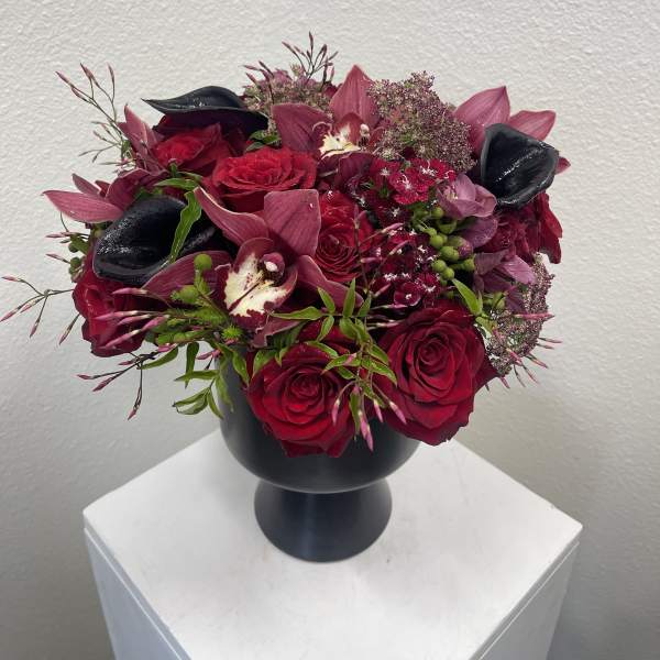 Red and burgundy floral arrangement in a black vase