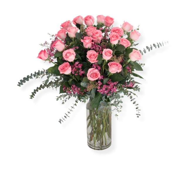Pink roses arranged in a clear glass vase with small pink filler flowers