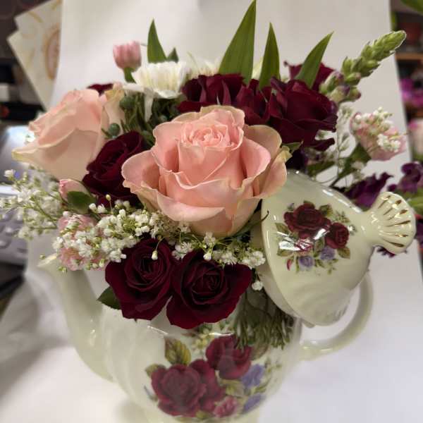 Pink and burgundy roses arranged in a floral teapot
