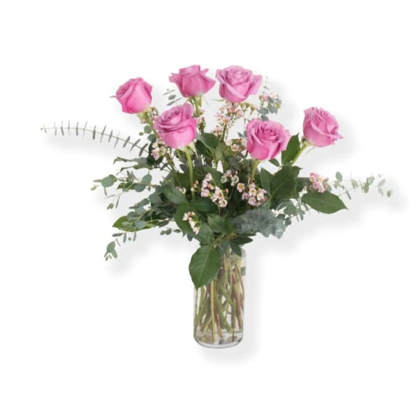Pink roses arranged in a clear glass vase with airy greenery