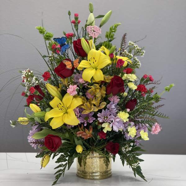 Mixed bouquet with yellow lilies, red roses, and a gold vase