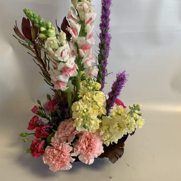 Tall mixed floral arrangement with pink, yellow, white, and purple blooms