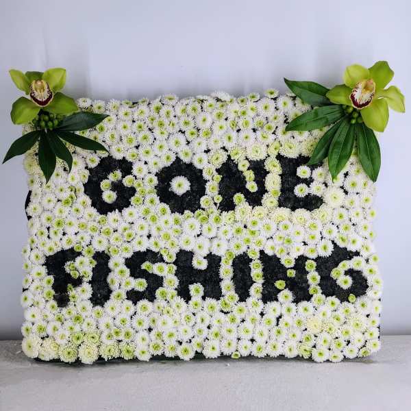 White floral tribute with green orchids and leaves spelling "PAPA"