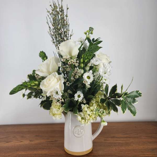 White floral arrangement in a ceramic pitcher vase