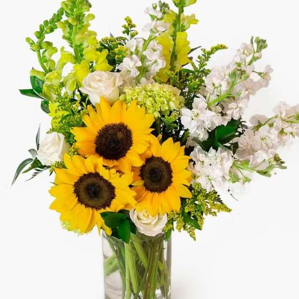 Sunflowers and white flowers arranged in a clear glass vase