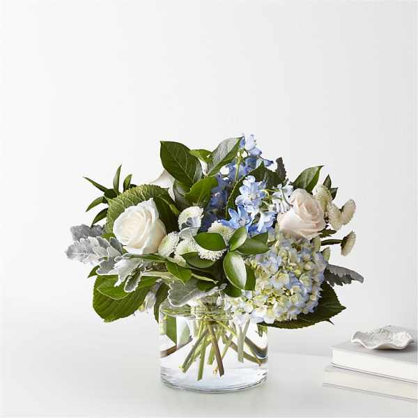 White roses and blue flowers in a clear glass vase