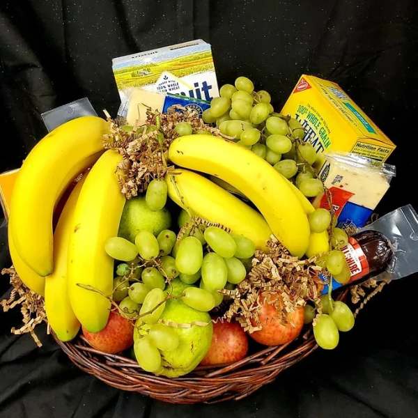 Fruit basket with bananas, grapes, apples, and packaged snacks