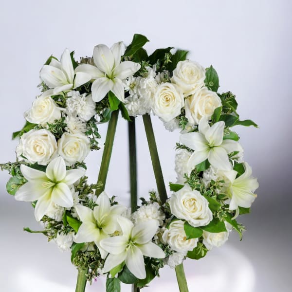 White floral wreath with roses and lilies on a stand