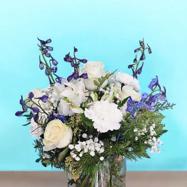 White and blue floral arrangement in a clear glass vase