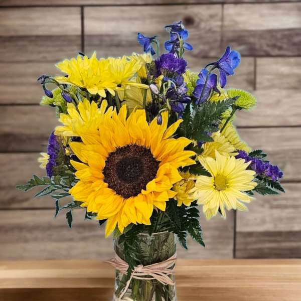 Sunflower bouquet in a glass vase with yellow and purple flowers
