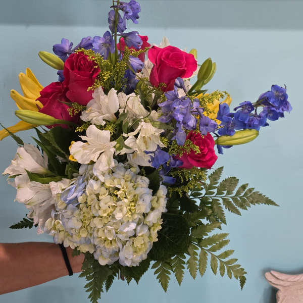 Bouquet of pink roses, white hydrangea, blue delphinium, and yellow lilies
