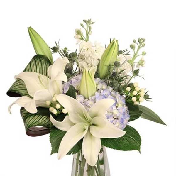 White lilies and pale hydrangeas in a clear glass vase