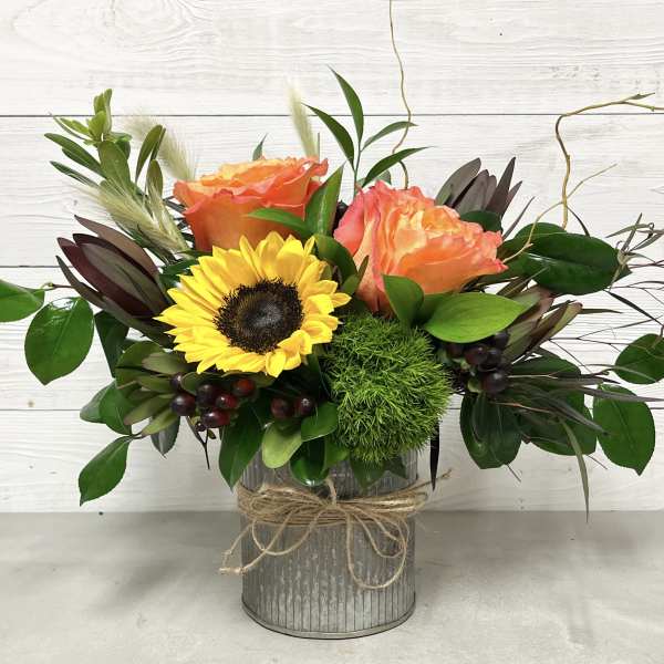 Bouquet of orange roses and a yellow sunflower in a metal vase