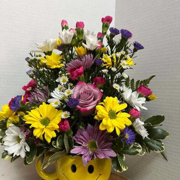 Mixed bouquet in a yellow smiley-face mug vase