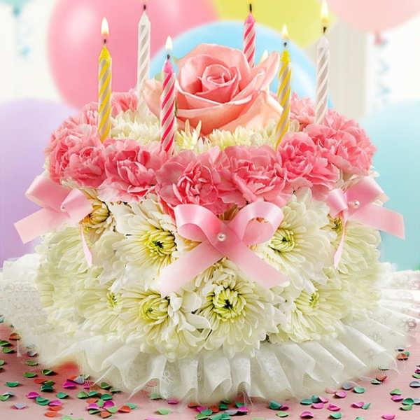 Pink and white floral cake with lit striped candles