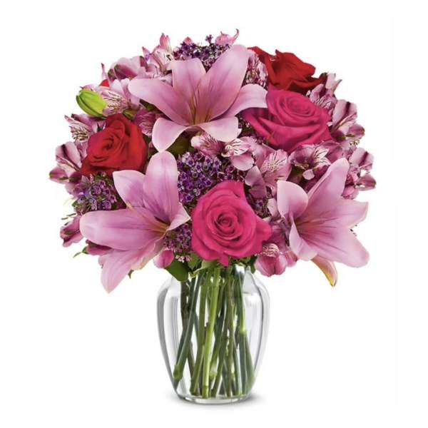 Pink lilies and roses arranged in a clear glass vase