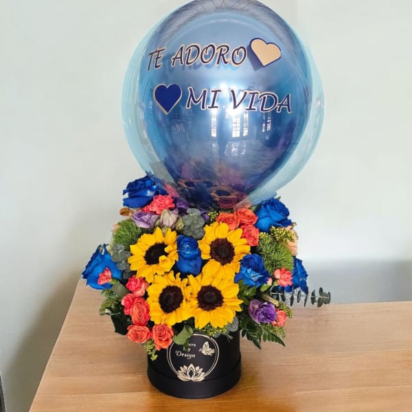 Blue balloon over a colorful flower arrangement in a black box