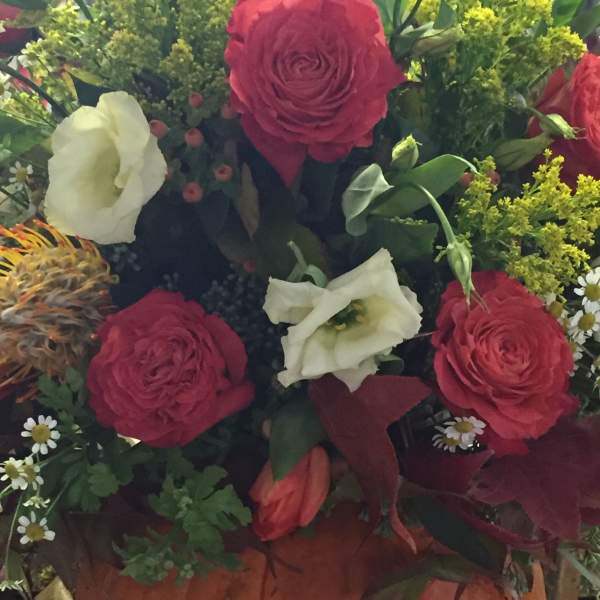 Bouquet of red and white flowers arranged in a pumpkin container