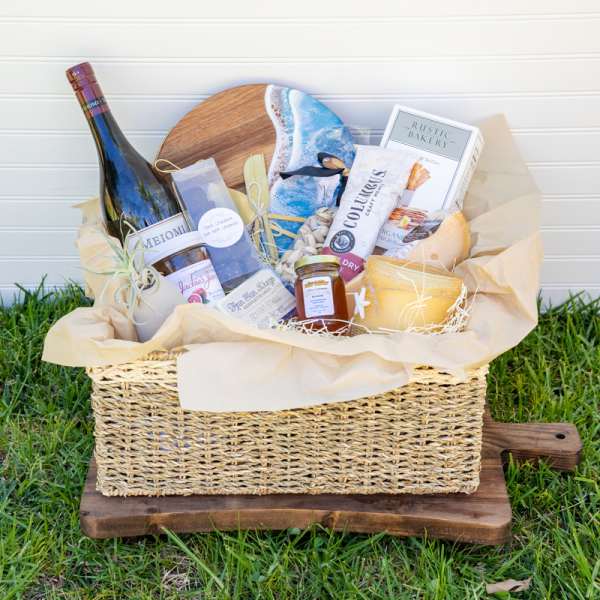 Gift basket with wine, snacks, and candles in a woven basket