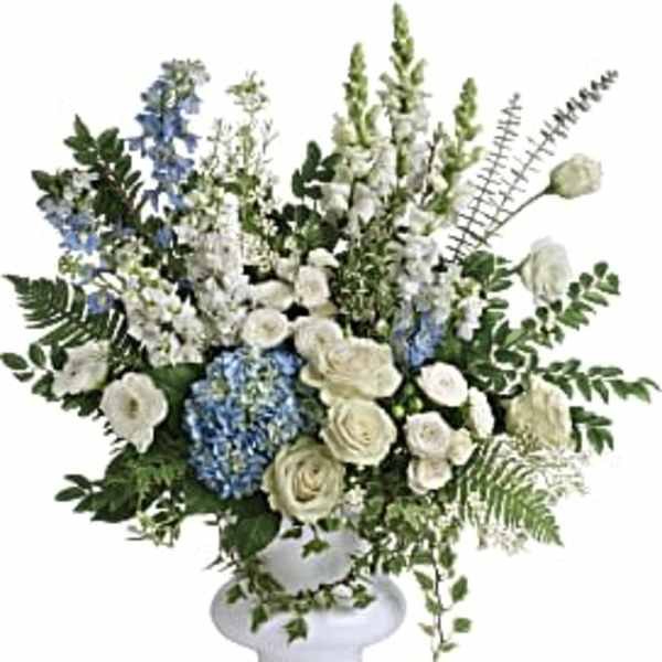 White and blue floral arrangement in a white pedestal vase
