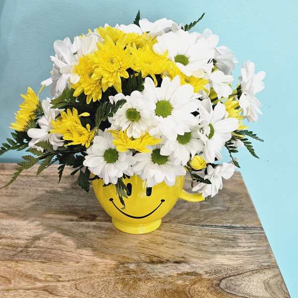 Yellow and white daisy bouquet in a smiley-face mug