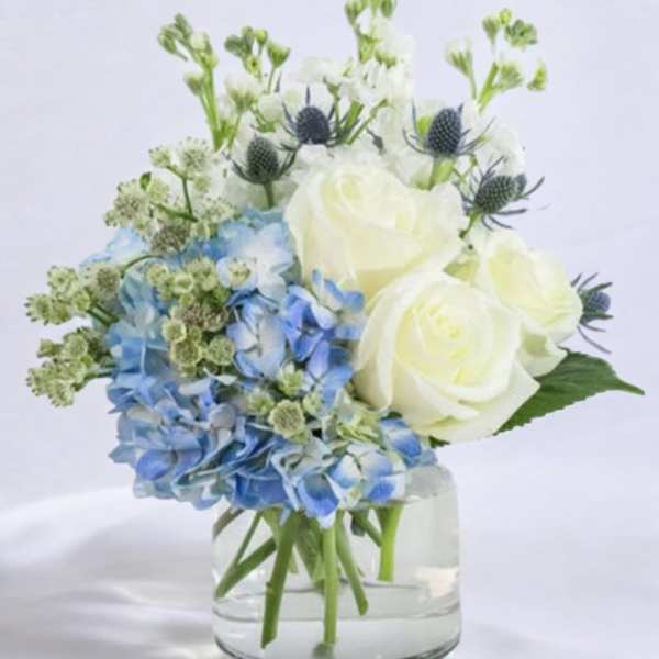 Blue hydrangeas and white roses in a clear glass vase