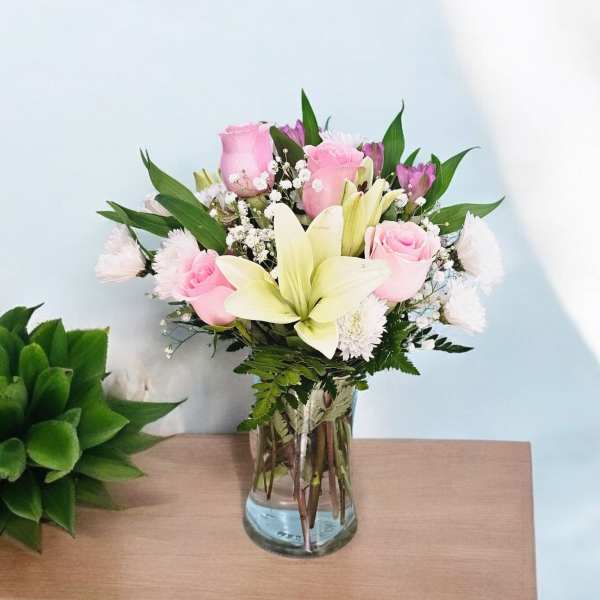 Pink roses and white lilies arranged in a clear glass vase