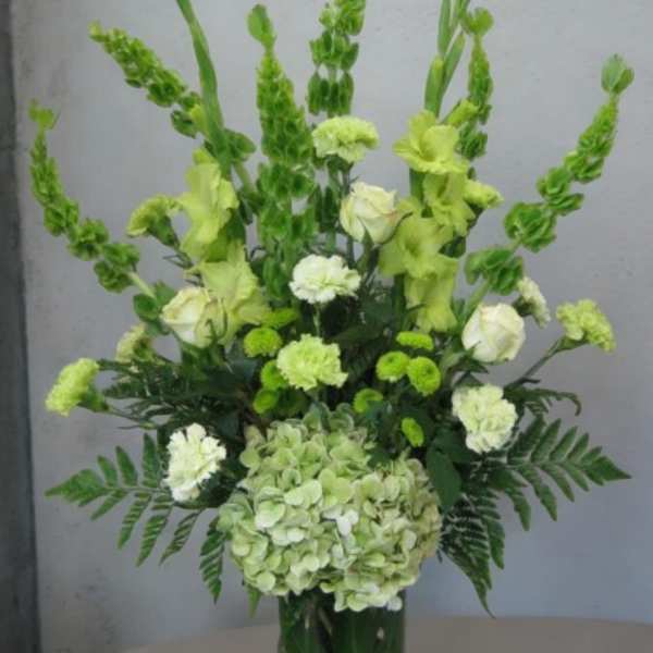 Green and white floral arrangement in a glass vase