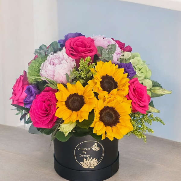 Bright mixed bouquet in a black round box with sunflowers and pink roses